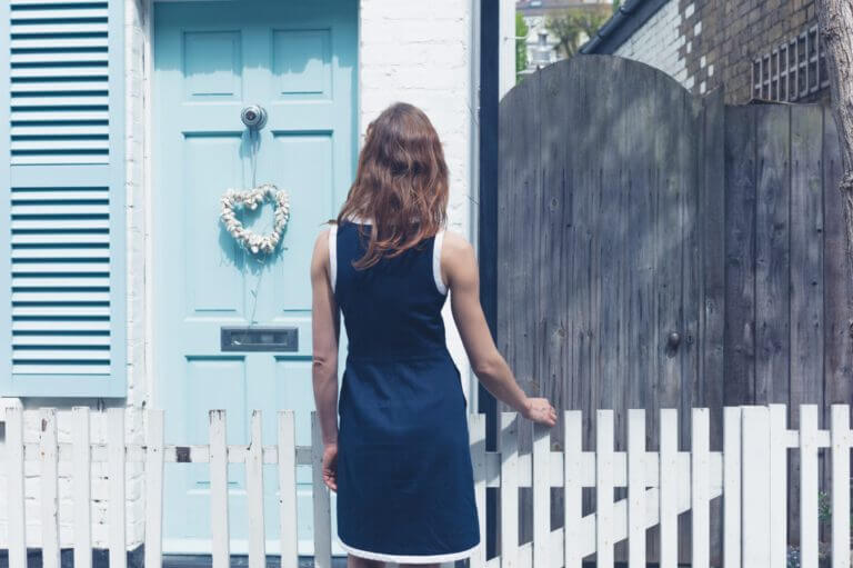 A lady looking at front door of a house