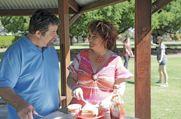 MyBudget clients Debbie and Alan at the park holding a bbq